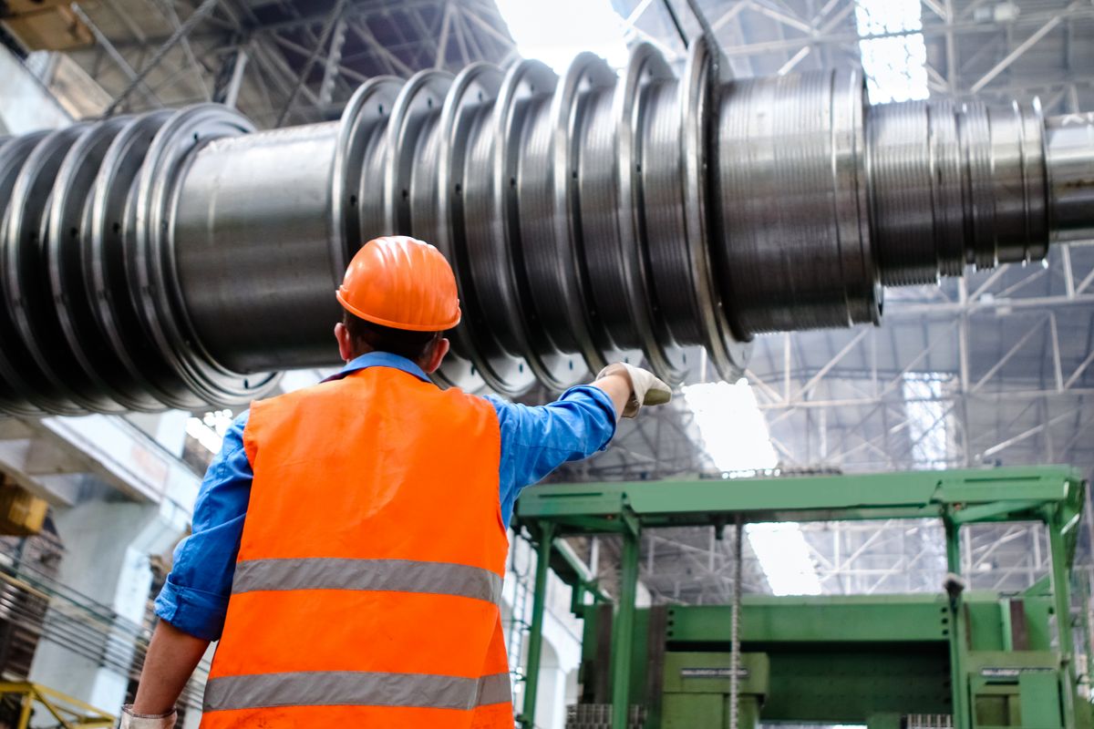 Tecnico con casco e gilet ad alta visibilità al lavoro su un grande rullo